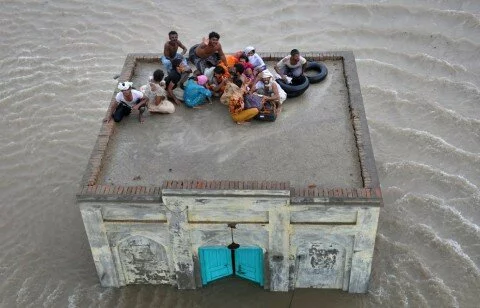 A family takes refuge on top of a mosque while awaiting rescue from flood waters 